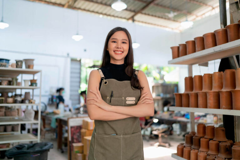 Female ceramist with apron hand confident chest in her workshop clay sculpture studio wondering what do I need to make a website