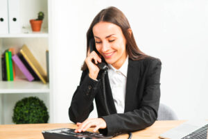 Smiling young businesswoman talking on telephone in the office to ask for outsourcing accounting services for small business