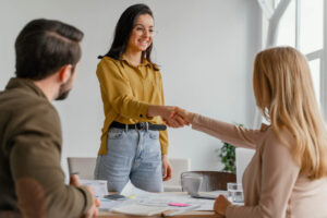 Businesswomen shaking hands at work happy to know when to hire your first employee