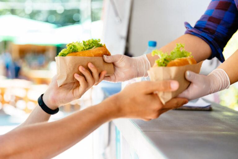 Close-up of man buying two hot dog in a food truck